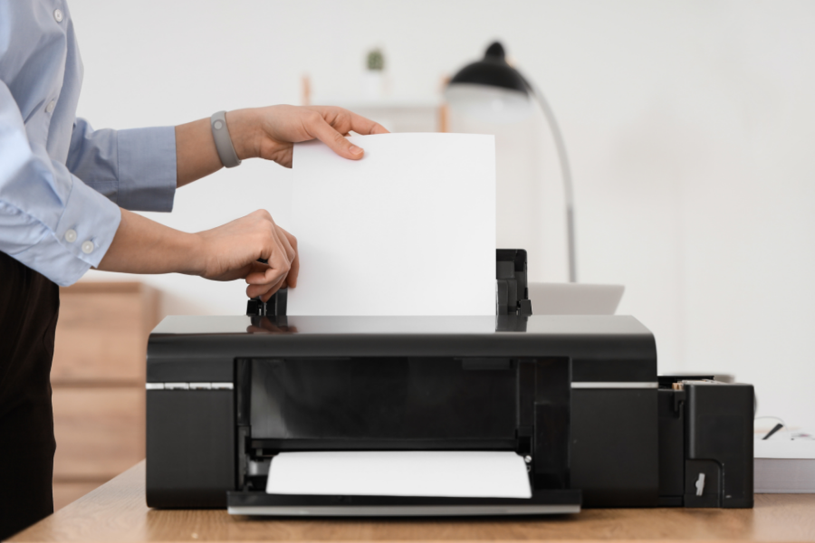 Person loading paper in a printer, points to Computers, Printing, and Copying page.