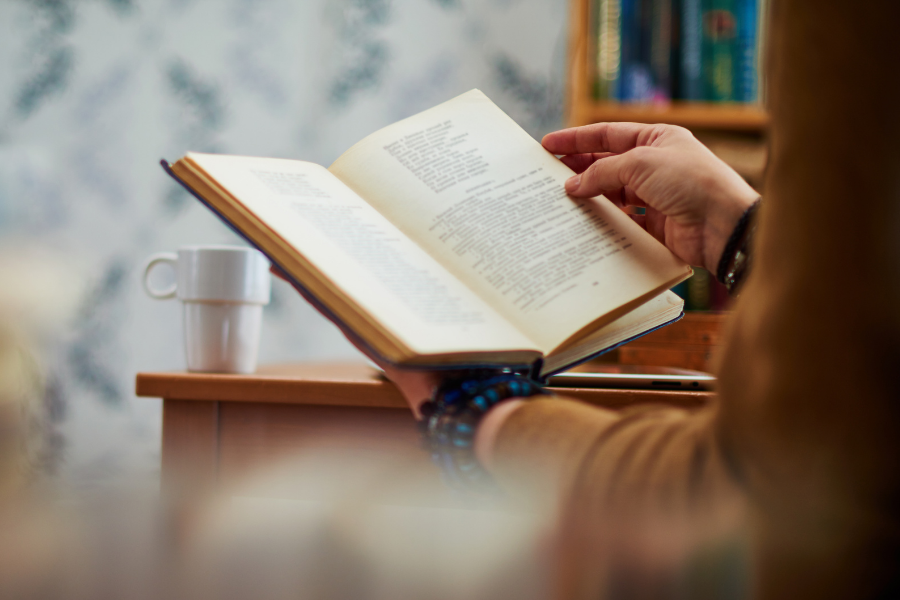 Person reading a book, points to suggest a title page.