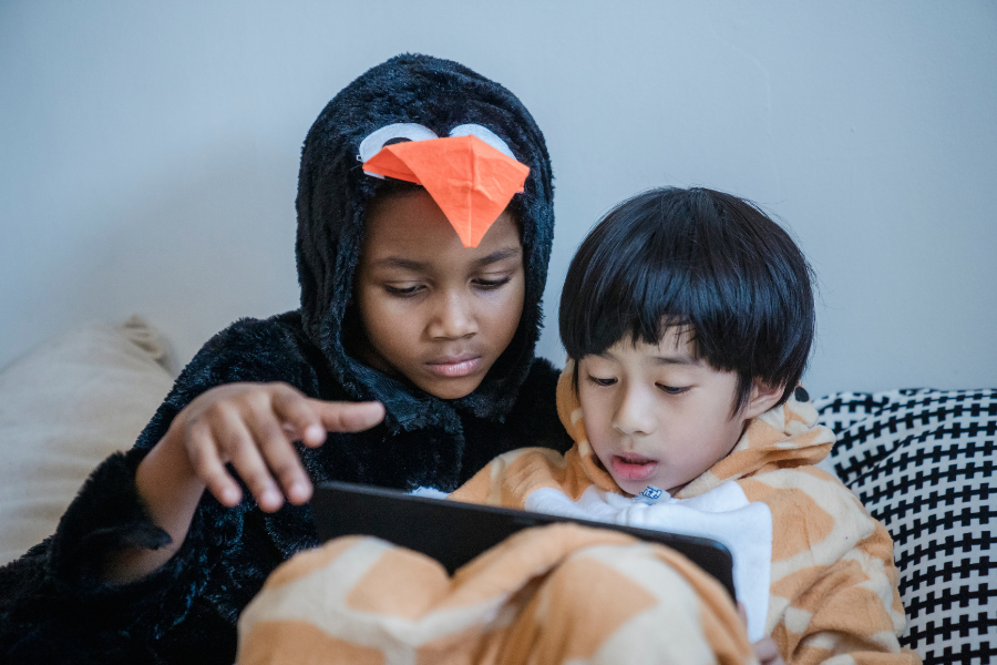 A couple of kids watch something on a tablet.